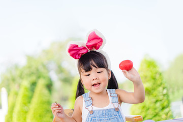 Cute little asian toddler girl wearing bunny ears on Easter day.Little asian Girl painting easter...