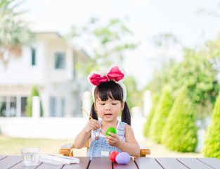 Cute little asian toddler girl wearing bunny ears on Easter day.Little asian Girl painting easter...