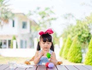 Cute little asian toddler girl wearing bunny ears on Easter day.Little asian Girl painting easter...