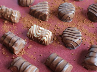 Chocolate candies on red background. Chocolate assortment and cacao splash.