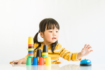 Little asian toddler girl playing stacking cups learning materials in a montessori methodology school being manipulated by children.Montessori classroom for the learning of children in mathematics.