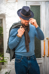A man in a hat close-up. Bracelets made of stones on a man&rsquo;s hand. Talismans, amulets on a man&rsquo;s hand. A man in a blue sweater and scarf.