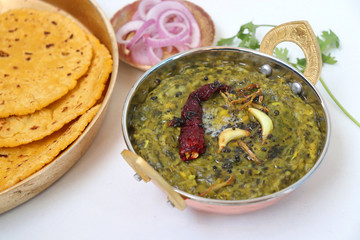 Sarson ka saag and Makke di roti. mustard leaves curry. its a popular punjabi winter dish made using corn meal & mustard leaves. served with onions and green chili in copper vessels. with copy space.