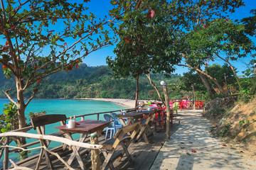 idyllic beach restaurant in thailand with wooden chairs