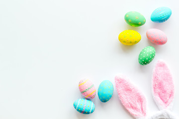 Easter symbols. Bunny and painted eggs on white background top-down frame copy space