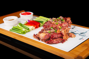 spicy Chinese meat with fresh vegetables on a wooden board. on a black isolated background.