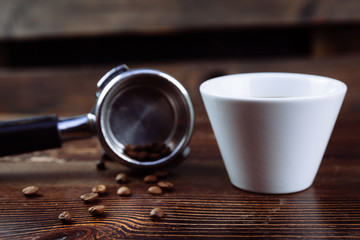 A cup of black coffee and filter holder of espresso.
