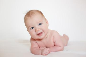 small child, baby lies on his stomach and smiles. On a white background. Newborn baby. three months old baby. A baby of European appearance.