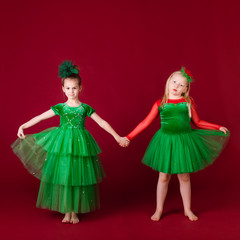 Beautiful little girl princesses dancing in luxury green dress isolated on red background. Carnival party with costumes