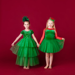 Beautiful little girl princesses dancing in luxury green dress isolated on red background. Carnival party with costumes