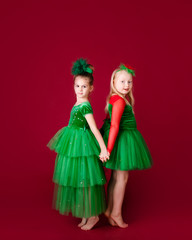 Beautiful little girl princesses dancing in luxury green dress isolated on red background. Carnival party with costumes