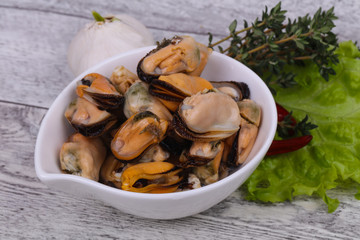 Pickled mussels in the bowl served pepper, garlic and salad