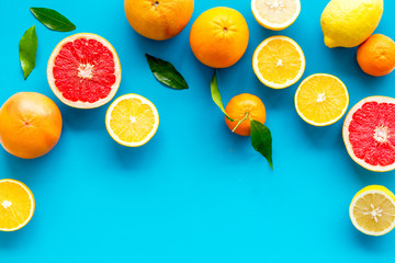 Citrus fruits frame - halfs of lemons, grapefruits, leaves - on blue background top-down copy space
