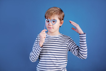 Birthday party and young boy with glasses in hats and props on blue background