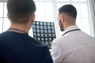 Two male doctors looking involved while analyzing MRI results