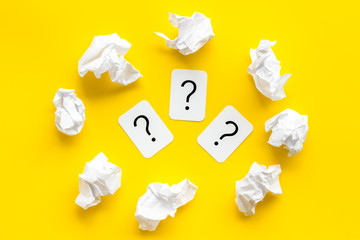 Writer's block concept. Question mark among crumpled paper on yellow background top-down