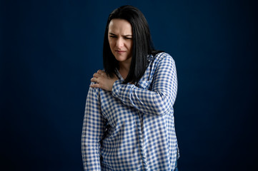 Young woman dressed casually has shoulder pain