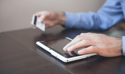 Man holding credit card and using tablet. Online payment and shopping