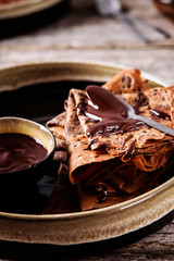 Chocolate Crepes with chocolate sauce on vintage wooden table. Selective focus