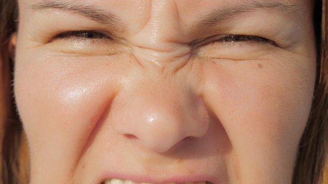 Anger expression on female face. Crop face of angry woman with frowning brows and wrinkled nose looking at camera