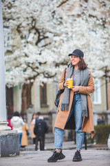 young stylish woman walking by street with coffee cup