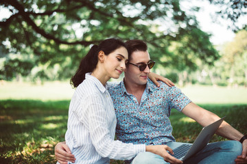 Couple young teen lover sitting and using laptop computer together at park,Romantic and enjoying in moment of happiness time,Happy and smiling
