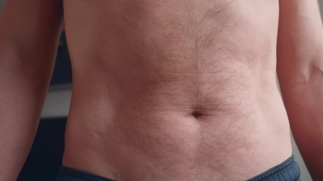 Adult caucasian man puffs his hairy stomach, then strains it. Big close-up view