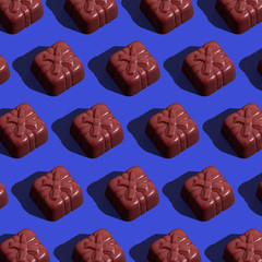 Chocolate candy on classic blue background. Seamless patter. Background image. 
