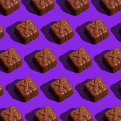 Chocolate candy on violet background. Seamless patter. Background image. 