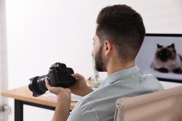 Professional photographer with camera working at table in office