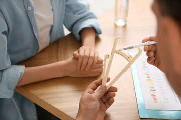 Nutritionist consulting patient at table in clinic, closeup