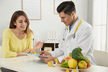 Nutritionist consulting patient at table in clinic