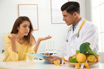 Nutritionist consulting patient at table in clinic