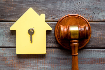 Property auction concept. Judge gavel near house on dark wooden background top-down