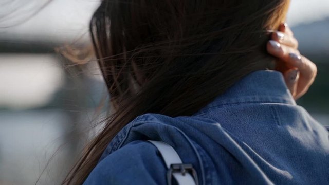 Close back view of girl dark hair gentle movement in the air in slow motion. The wind blows dark hair shining in the sun at sunset. Macro video. Hair in the wind.