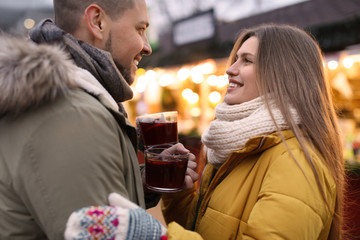 Happy couple with mulled wine at winter fair