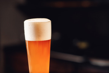 Close up gold background texture of yellow lager beer with froth and bubbles in glass, soft focus