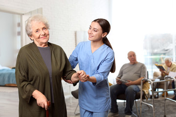 Nurse taking care of elderly woman in geriatric hospice - obrazy, fototapety, plakaty