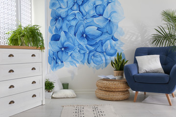 Stylish living room with blue flowers painted on wall. Floral pattern in interior design