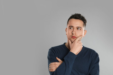 Portrait of thoughtful young man on grey background. Space for text