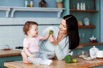 Mother feeds baby broccoli and vegetables. Proper and healthy nutrition
