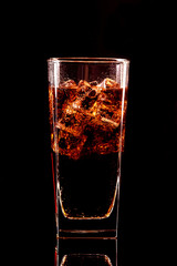 Cola glass with ice cubes and droplets, isolated on black background