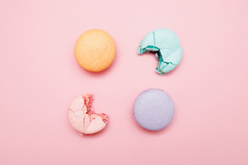 Minimalism, bitten macaroons on pink background, top view. Concept reducing interest rates on loans in banks, taxes