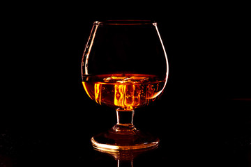Whiskey with ice in glass isolated on black background