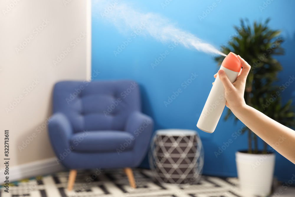 Poster Woman spraying air freshener at home, closeup