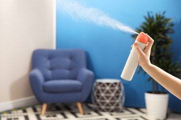 Woman spraying air freshener at home, closeup