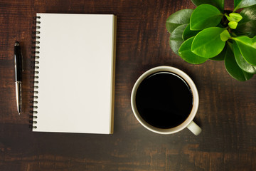 Obraz na płótnie Canvas Top view of open school notebook with blank pages, Pen, Plant and Coffee cup on wooden table background. Business, office or education concept with copy space.