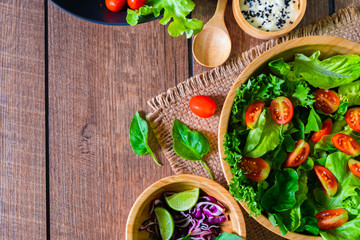 Fresh green vegetable salad. above of cherry tomato, onion, spinach and lettuce in wooden bowl with spoon, salad sesame dressing. Home made, Diet food for tasty and healthy meal. Top view, copy space.