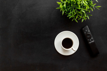 Television air recording concept. TV remote on black background top-down copy space