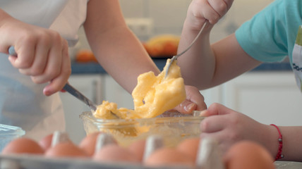 Hands of two children mixing butter with sugar and eggs